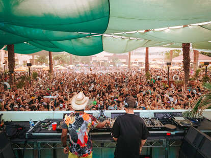 two djs in front of a large crowd below during a daytime set at splash house electronic music festival in palm springs, california
