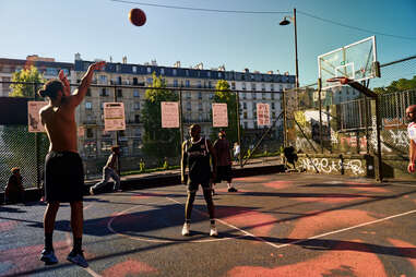 a basketball player shooting hoops at the Jemappes street ball court in Paris, France