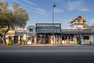 main street in fredericksburg, texas, with a couple walking a dog in front of quaint shops