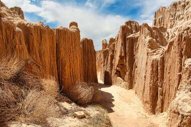 A path through a slot canyon, with ridged rock walls that look like layers of melted candle wax.