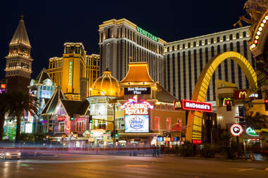 A nighttime photo of the Las Vegas Strip shows fast food chain, luxurious hotels, and a variety of other businesses aglow with their illuminated signage.