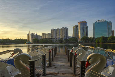 swan boats at sunset along lake eola in front of the orlando skyline