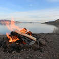 a campfire burning on the shore of a lake under blue sky, in Pyramid Lake, Nevada