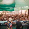 two djs in front of a large crowd below during a daytime set at splash house electronic music festival in palm springs, california